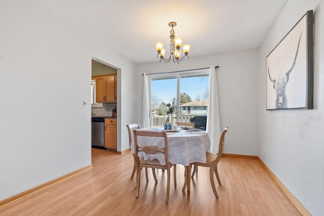 dining room with a textured ceiling, light wood-style flooring, baseboards, and a chandelier