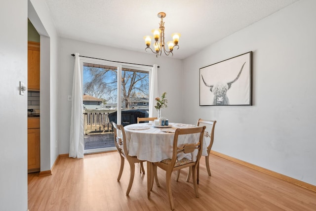 dining room with baseboards, light wood-style floors, an inviting chandelier, and a textured ceiling