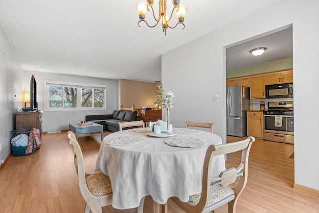 dining room with a notable chandelier, baseboards, and light wood-style floors