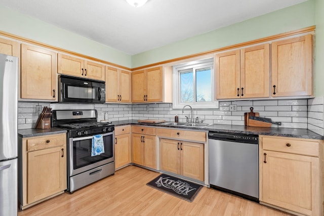 kitchen featuring a sink, dark countertops, light brown cabinets, and stainless steel appliances