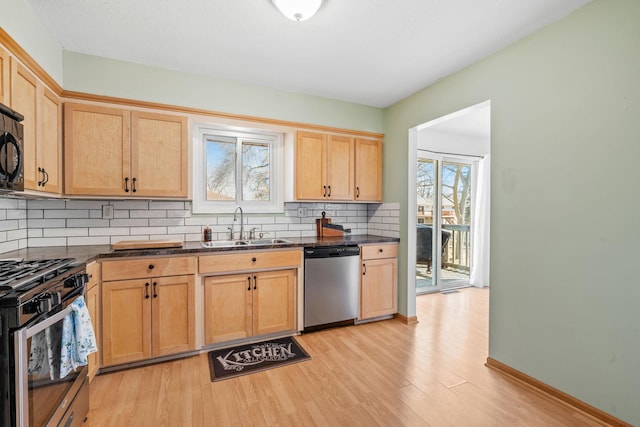 kitchen with a sink, dark countertops, light brown cabinets, and stainless steel appliances