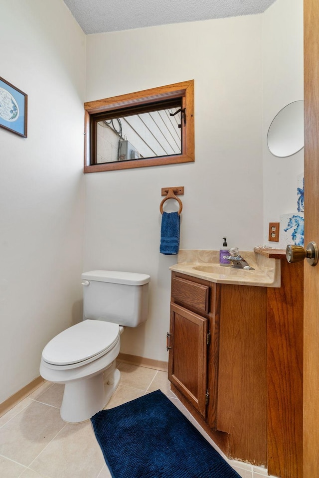 half bath with baseboards, toilet, vanity, and tile patterned flooring