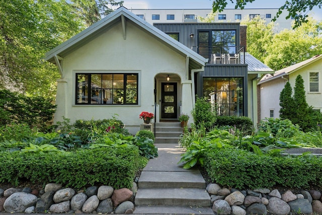 exterior space featuring a balcony, metal roof, board and batten siding, and stucco siding