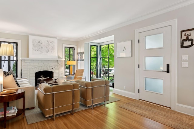 living room with a brick fireplace, wood finished floors, baseboards, and ornamental molding