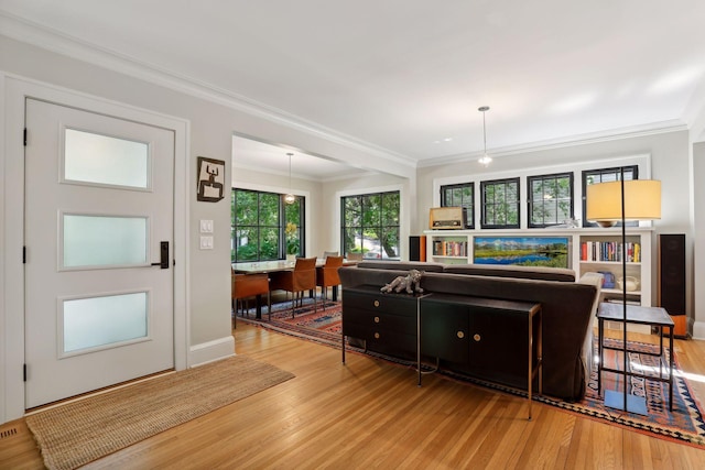 living room with wood finished floors, baseboards, and ornamental molding