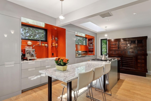 kitchen featuring visible vents, pendant lighting, modern cabinets, light wood-style flooring, and light stone counters