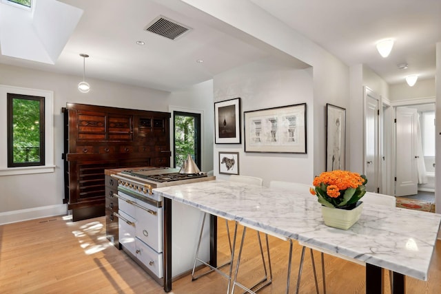 kitchen featuring visible vents, plenty of natural light, a kitchen island, and light wood-style floors