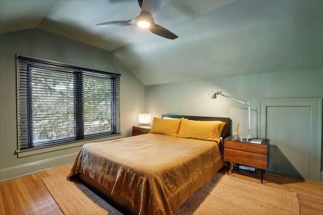 bedroom with ceiling fan, baseboards, wood finished floors, and vaulted ceiling