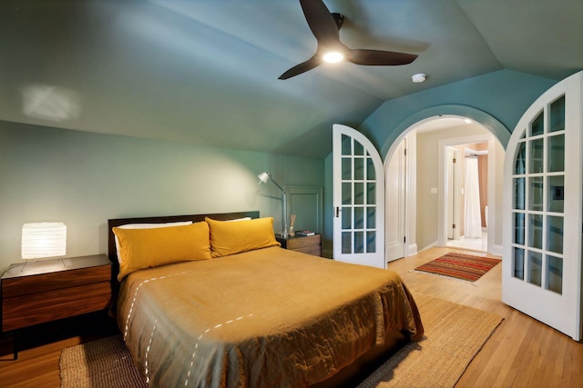 bedroom featuring wood finished floors, arched walkways, ceiling fan, vaulted ceiling, and french doors