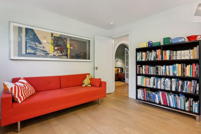 sitting room featuring arched walkways and wood finished floors