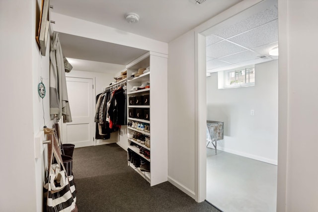 spacious closet featuring dark carpet and a drop ceiling