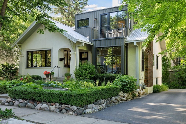 view of front of house featuring stucco siding, a balcony, and board and batten siding