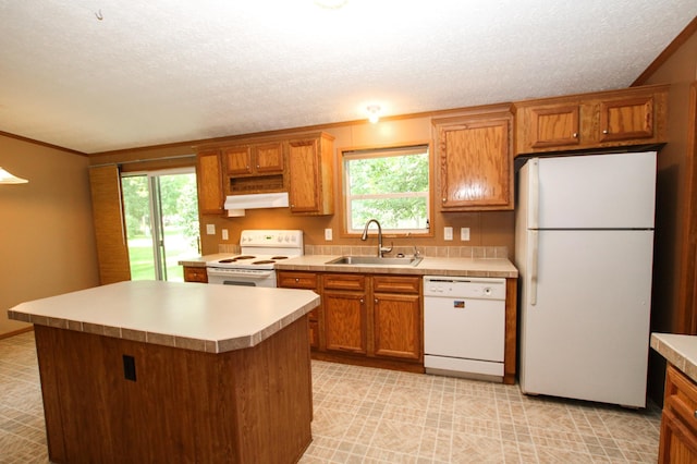 kitchen featuring light countertops, white appliances, a sink, and brown cabinets