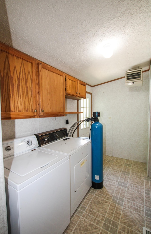 laundry area with cabinet space, independent washer and dryer, and a textured ceiling