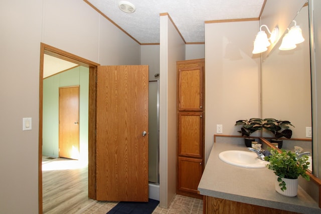 bathroom featuring vanity, wood finished floors, an enclosed shower, a textured ceiling, and crown molding