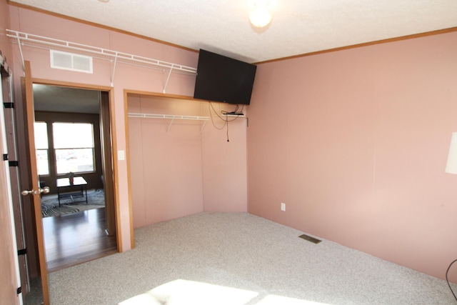 unfurnished bedroom featuring carpet, crown molding, visible vents, and a closet