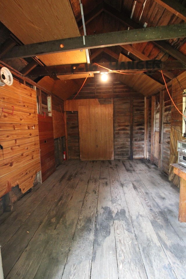 interior space featuring wood-type flooring, wooden walls, and vaulted ceiling