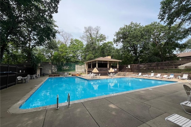 community pool with a patio area and fence