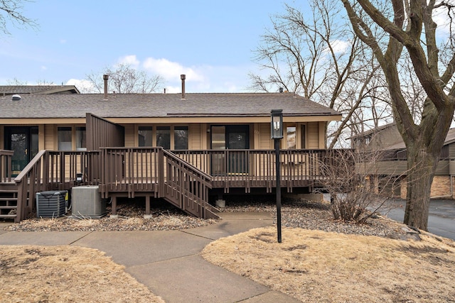 ranch-style house featuring cooling unit, covered porch, and roof with shingles