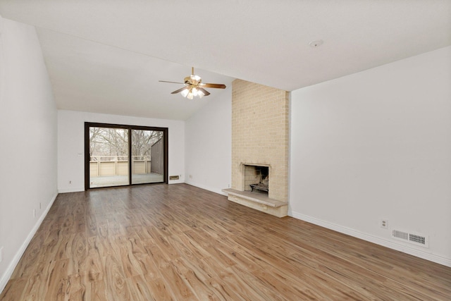 unfurnished living room with wood finished floors, a ceiling fan, visible vents, lofted ceiling, and a brick fireplace