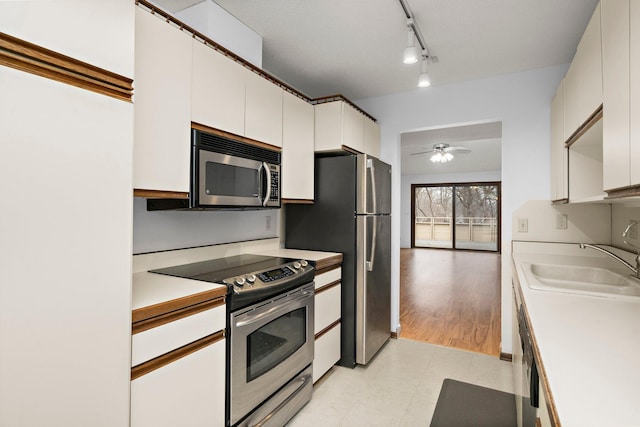 kitchen with ceiling fan, light countertops, appliances with stainless steel finishes, white cabinetry, and a sink