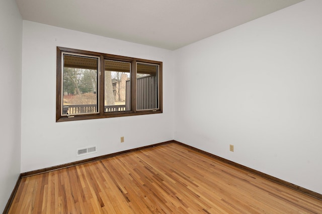 spare room featuring baseboards, visible vents, and light wood finished floors