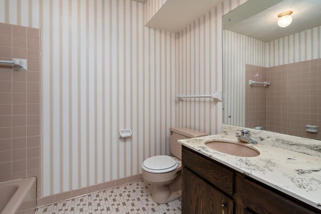 full bathroom with toilet, vanity, and wallpapered walls