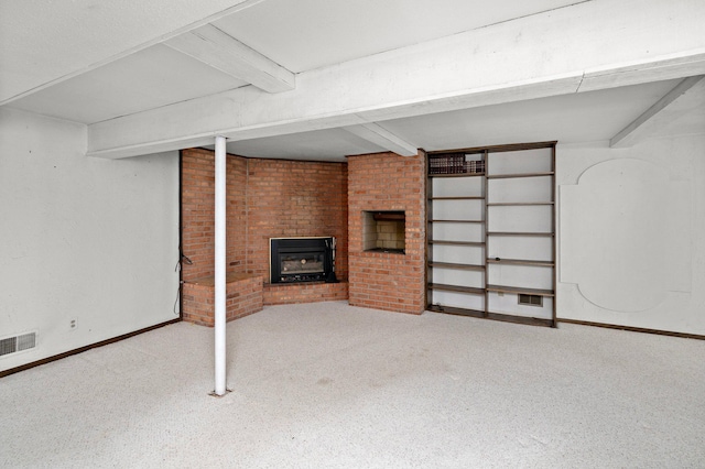 finished below grade area featuring visible vents, brick wall, baseboards, carpet floors, and a fireplace