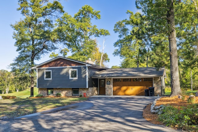 tri-level home featuring a garage, aphalt driveway, and a chimney