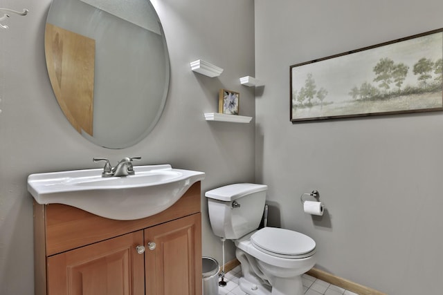 half bathroom with tile patterned flooring, baseboards, vanity, and toilet