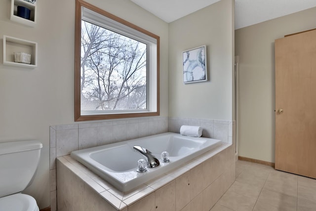 bathroom featuring toilet, a garden tub, baseboards, and tile patterned floors