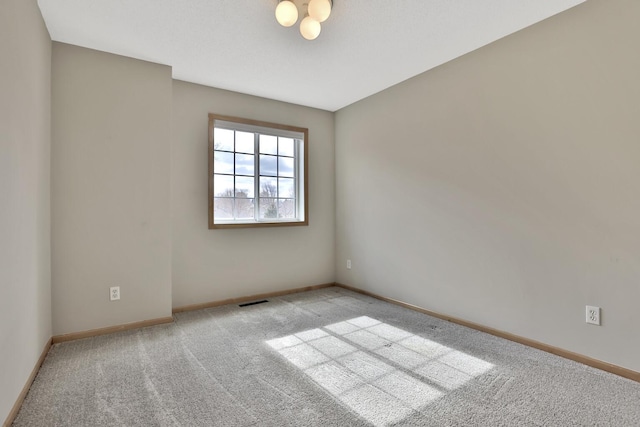 carpeted spare room featuring visible vents and baseboards