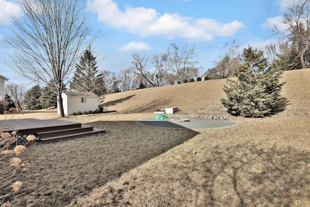 view of yard featuring an outdoor structure, a wooden deck, and a shed