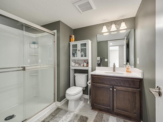 bathroom with vanity, visible vents, a stall shower, a textured ceiling, and toilet