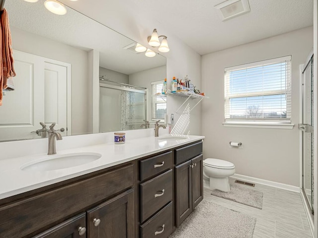 full bathroom with double vanity, visible vents, a shower stall, and a sink