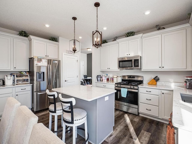 kitchen with white cabinetry, appliances with stainless steel finishes, a kitchen island, and dark wood-type flooring