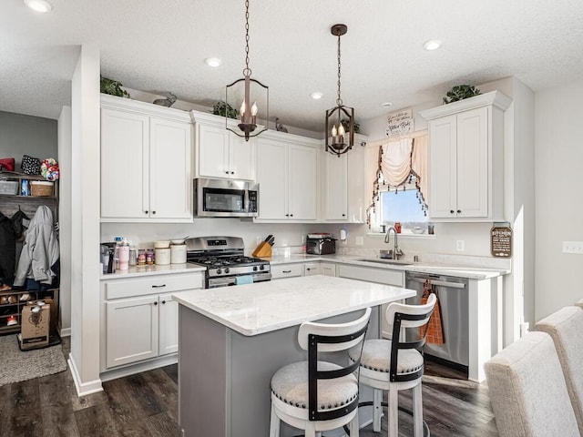 kitchen with a sink, a center island, a kitchen bar, stainless steel appliances, and dark wood-style flooring