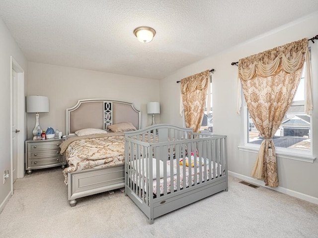 carpeted bedroom featuring baseboards, visible vents, and a textured ceiling