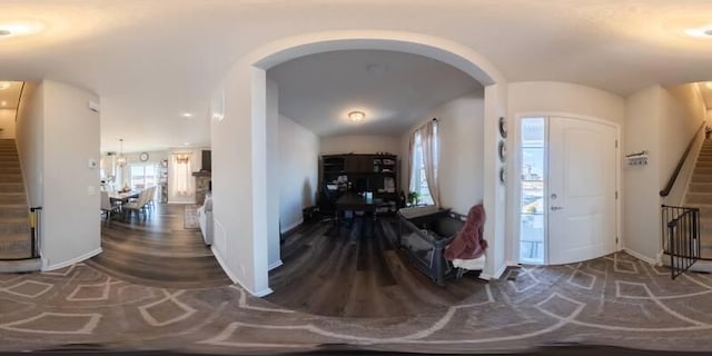 foyer entrance with baseboards, arched walkways, wood finished floors, and stairs