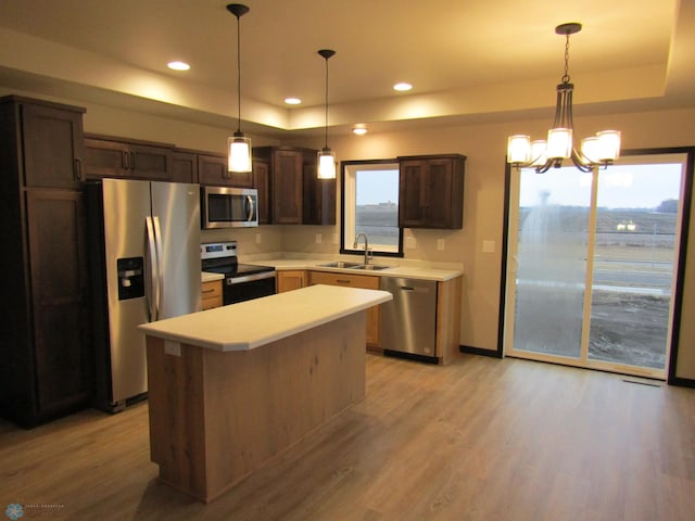 kitchen featuring light wood-style floors, stainless steel appliances, a sink, and a raised ceiling