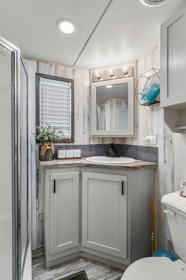 bathroom with toilet, a stall shower, and vanity