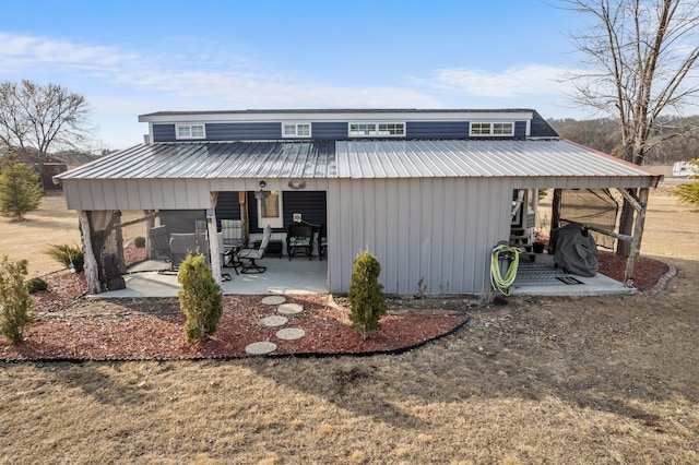 back of house with metal roof and a patio