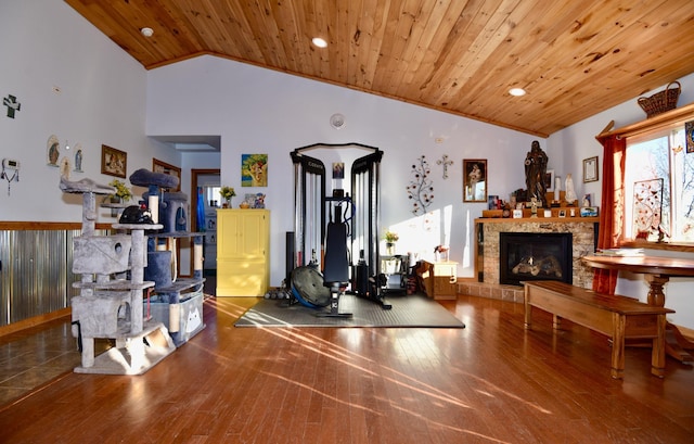 workout room with high vaulted ceiling, a stone fireplace, wooden ceiling, recessed lighting, and wood finished floors