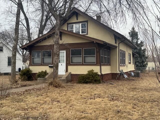 bungalow with central air condition unit, a chimney, and stucco siding