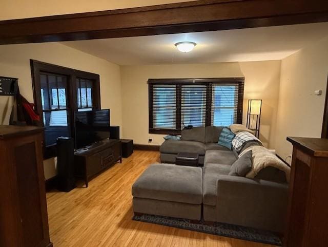 living area with light wood-style floors, beam ceiling, and baseboards