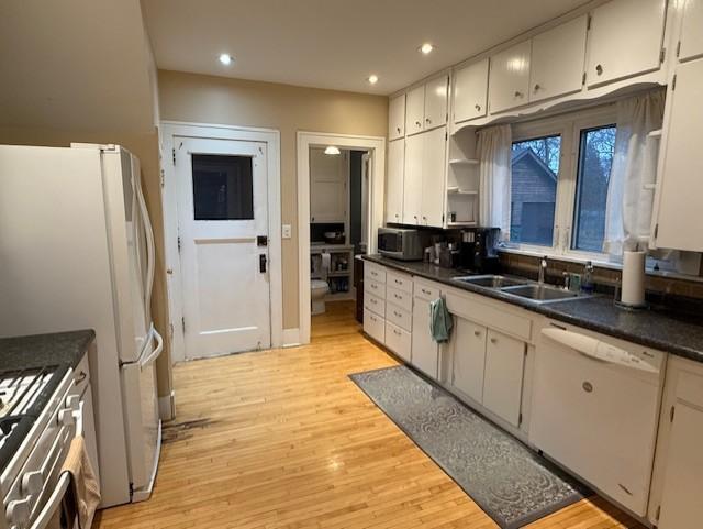 kitchen with dark countertops, recessed lighting, appliances with stainless steel finishes, light wood-style floors, and a sink