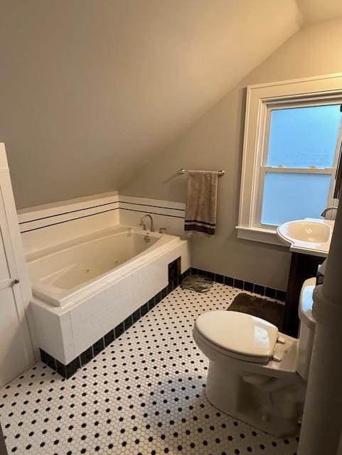 bathroom with lofted ceiling, tile patterned flooring, a garden tub, toilet, and vanity