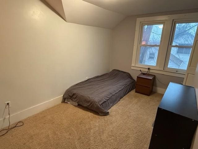 bedroom with light carpet, lofted ceiling, and baseboards