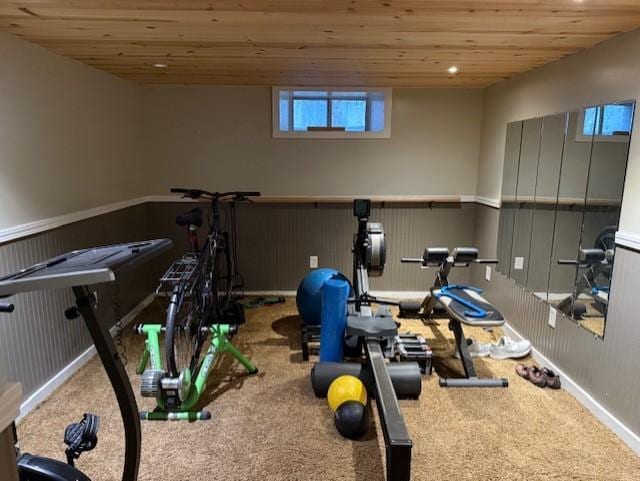 workout room featuring carpet floors, wooden ceiling, and wainscoting