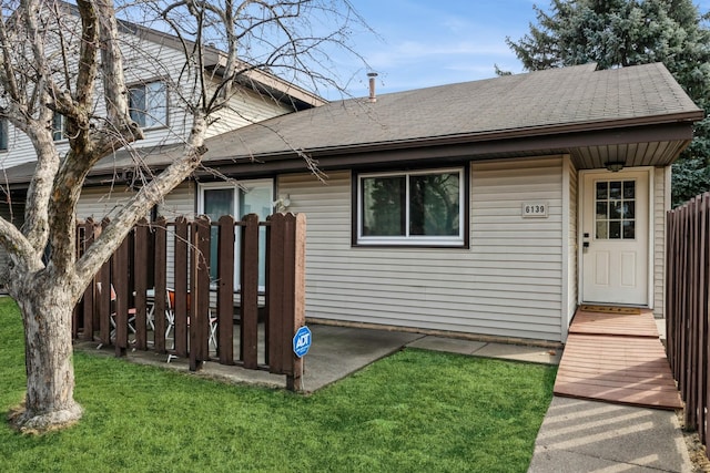 exterior space featuring a lawn and a shingled roof